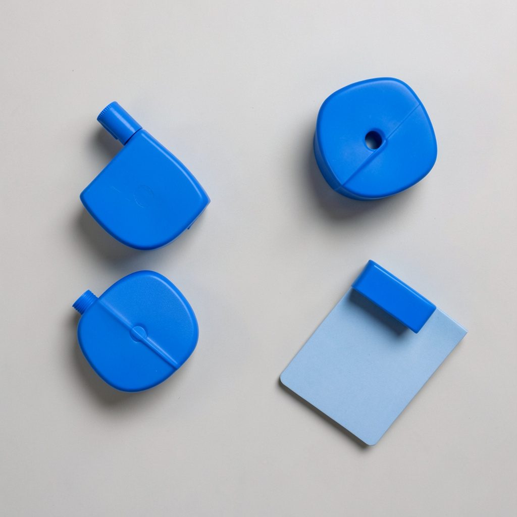 Overhead flat-lay photograph of a desk with a small notebook, pen and folded notes arranged on a muted slate-blue background, soft daylight, calm and focused study mood